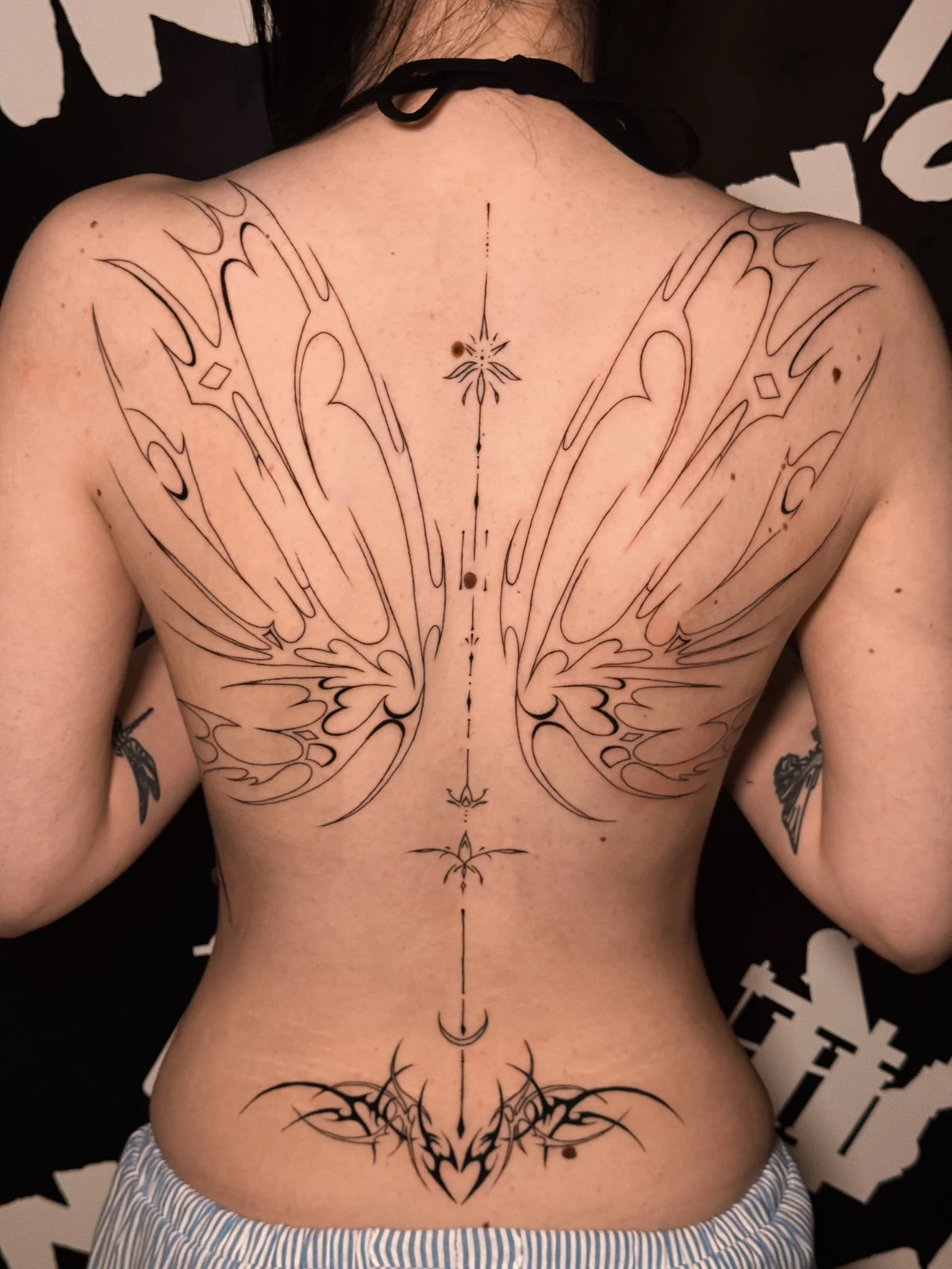 Großflächiges, symmetrisches Fineline-Rückentattoo mit abstrakten Flügeln und ornamentalen Linien – Arbeit von Merci, Skin City Tattoo.